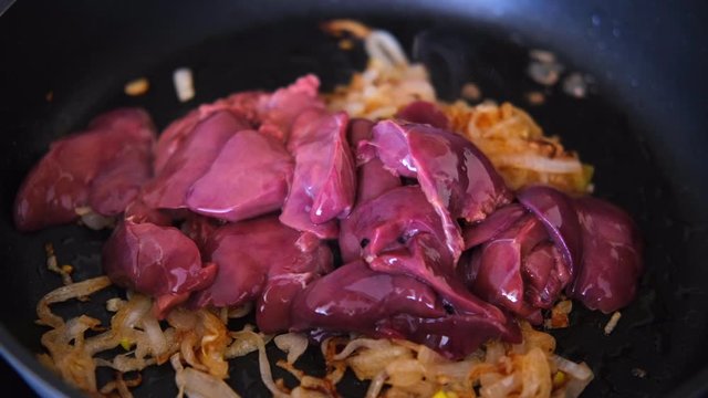 chicken liver with onion fried in the pan with a wooden kitchen spatula