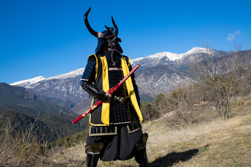 man dressed in samurai armor. He is at the mountains