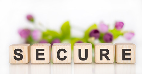 SECURE - financial business concept. Wooden cubes on a white table. In the background are pink...