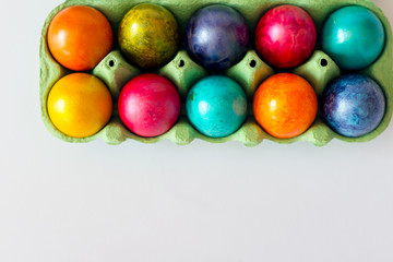 Fototapeta na wymiar Top view of colorful eggs in the carton box on white background. Easter holiday concept with copy space.