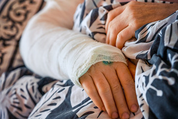 Woman lies in bed with a cast hand