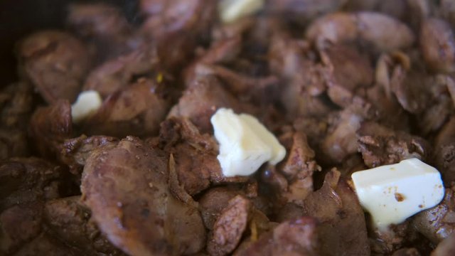chicken liver with onions fried in the pan with a wooden kitchen spatula