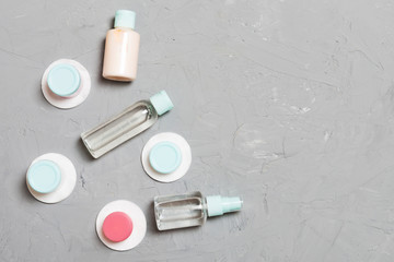 Top view of means for face care: bottles and jars of tonic, micellar cleansing water, cream, cotton pads on gray background. Bodycare concept with empty cpace for your ideas