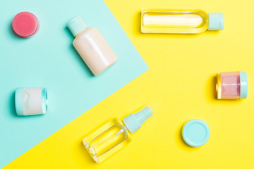 Top view of cosmetic containers, sprays, jars and bottles on yellow and blue background. Close-up view with empty space for your design