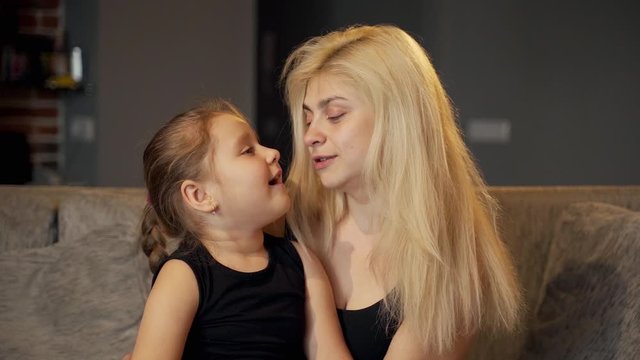 Games at home: A beautiful girl kisses with her cute daughter after play in the jenga tower. The girls are laughing and smiling. Slow. Shot in 100 fps and slowed to 50