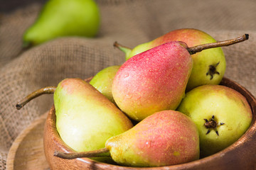 Pears in a wooden bowl on a brown wooden table. Seasonal fruits