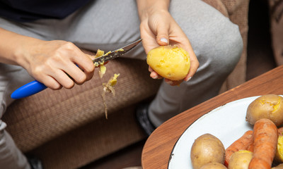 Girl peeling boiled potatoes with a knife