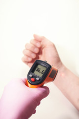 hand in pink glove holds ir thermometer normal temperature