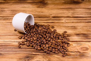 White cup and scattered coffee beans on wooden table
