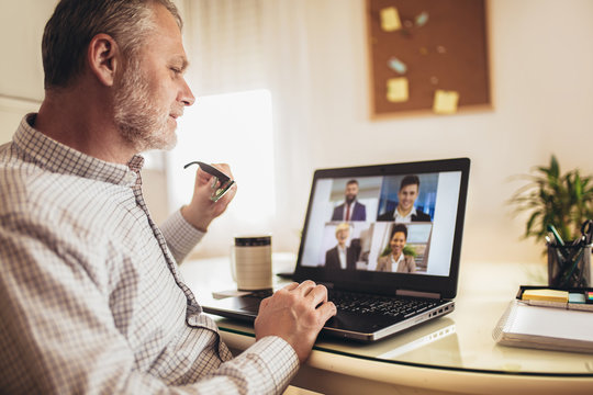 Man Working From Home Having Online Group Videoconference On Laptop