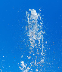 Obraz premium Splashing water from a fountain on a background of blue sky