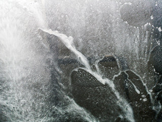 Auto glass in foam and water at a car wash as a backdrop
