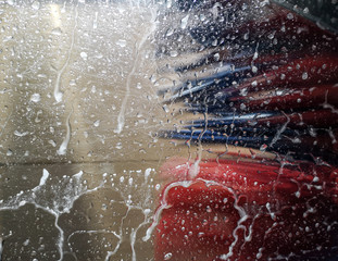 Auto glass in foam and water at a car wash as a backdrop.