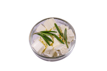 Chopped feta cheese and rosemary in glass bowl isolated on a white background