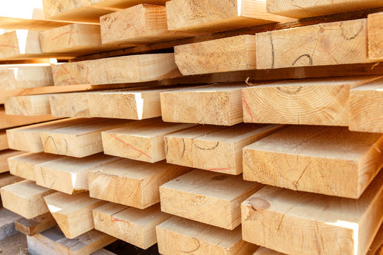 Stack of new wooden studs at the lumber yard. Timber on the construction site to dry. Background of sawed and processed wood of coniferous breeds.