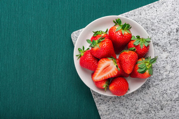 A plate of fresh strawberries on marble board, copy space