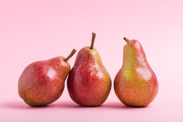 Three fresh red bartlett pears over pink background