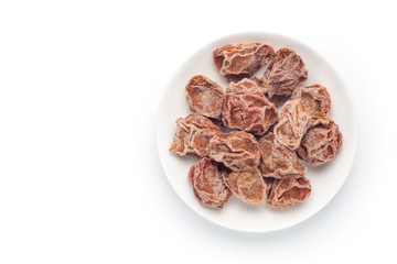 Preserved plums in a ceramic dish isolated on white background. Chinese snacks. Top view.