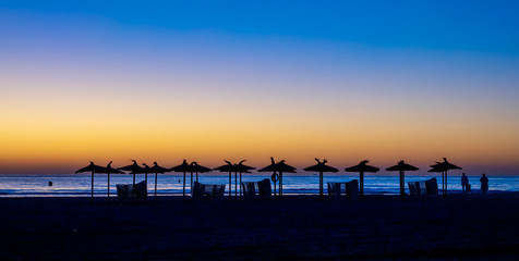 Silhouettes of umbrellas at a beach and sunrising