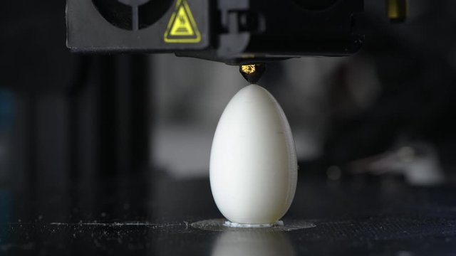 4K The 3D printer finishes printing white plastic model of egg. modern technology.