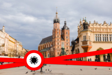 Coronavirus, Covid 19 pandemic, Quarantine concept. White sign with model of Coronavirus molecule on a red warning fencing ribbon on a blurred background of main square of Krakow, Poland