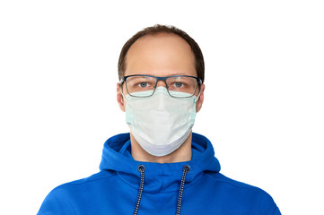 Man in glasses wearing a face protection surgical mask, isolation, protective for spreading of Coronavirus Disease 2020. Portrait of man with face mask against SARS-CoV-2. Blue hoodie.