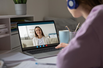 Pc screen view over woman shoulder, two girls best friends chatting using virtual modern video conference application communicating from home enjoy distant talk. Teacher teach learner remotely concept