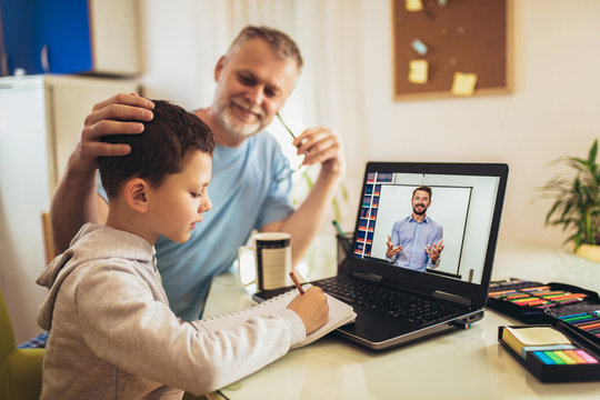 Schoolboy educate online. Father helps his son with home work. Boy in video conference with teacher on laptop at home.