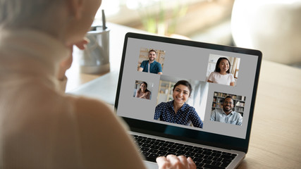 Woman rear back view sitting at desk over her shoulder laptop screen, over grey background photos...