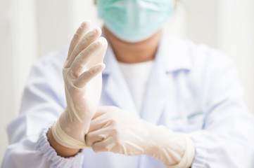Woman doctor putting white latex medical gloves on white wall background.Surgeon wearing gloves...