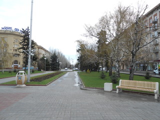 Naklejka premium Spring's bulvar with a trees, sittina and little monuments figures