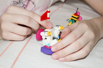 Children's hands collecting figures from a multi-colored constructor. Spending time at home.
