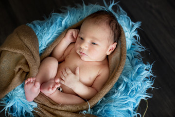 Cute little newborn baby boy, sleeping in basket with wrap