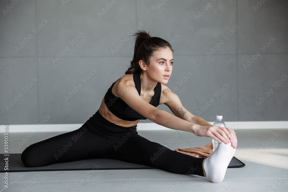 Canvas Prints Photo of young athletic woman stretching her leg while working out