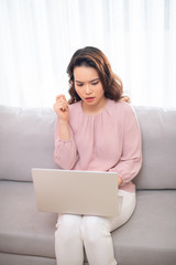 Confused Asian woman when using laptop on sofa at home.