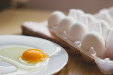 eggs in package and yolk on a white plate on the table