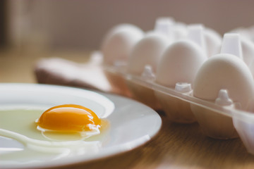 eggs in package and yolk on a white plate on the table