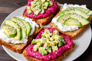 Variation of healthy rye sandwiches with avocado beetroot and cream cheese on a plate.  Delicious snacks and toast. Food composition, tasty italian meal. Close up