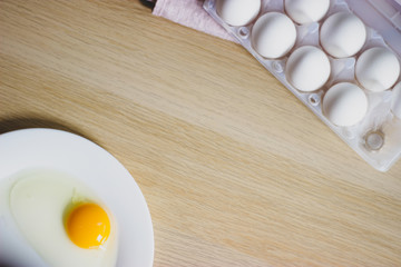 eggs in package and yolk on a white plate on the table