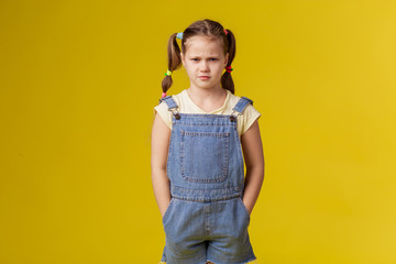 Girl child angry on a yellow background. Dissatisfied harmful hooligan. Gloomy evil upset nerves stress boredom. crisis bad behavior stubborn confident schoolgirl.  problem education. Protest bad mood