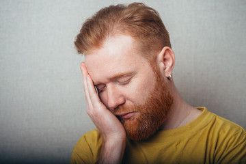 on a gray background man with a beard in a yellow shirt sleeping