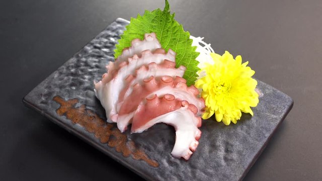 Sliced Japanese food octopus tako sashimi dinner meal on a turn table .