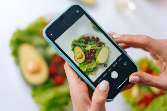 Close-up view of woman making photos vegetable salad with camera of cellphone to place pictures at social media resources. Concept of healthy eating.