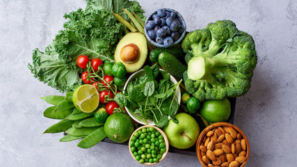Banner flat lay with healthy vegetarian meal ingredients. Raw food concept. A variety of organic fruits, nuts, berries and vegetables in wooden box on concrete background