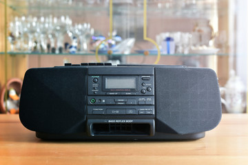Dusty radio cassette recorder on the blurred background of retro interior