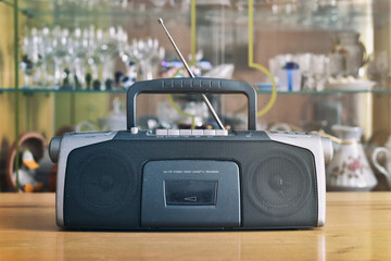 Dusty radio cassette recorder on the blurred background of retro interior