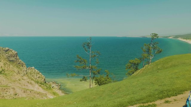 The view from the bird's eye view on Baikal Bay shaman. Green grass and blue water. Footage from drones. UNESCO world heritage