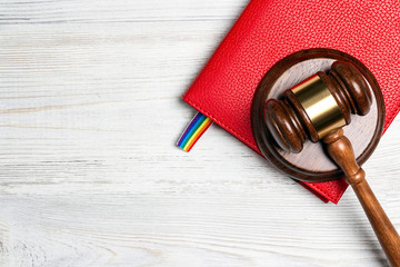Judge's gavel and notebook with a lgbt rainbow bookmark on wooden table.
