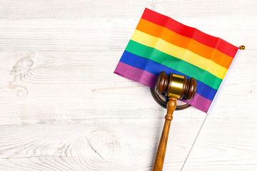Woden judge gavel symbol of law and justice with lgbt flag in rainbow colours on wooden background.