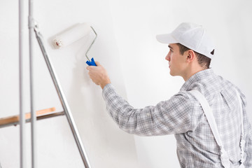 Young painter painting a white wall